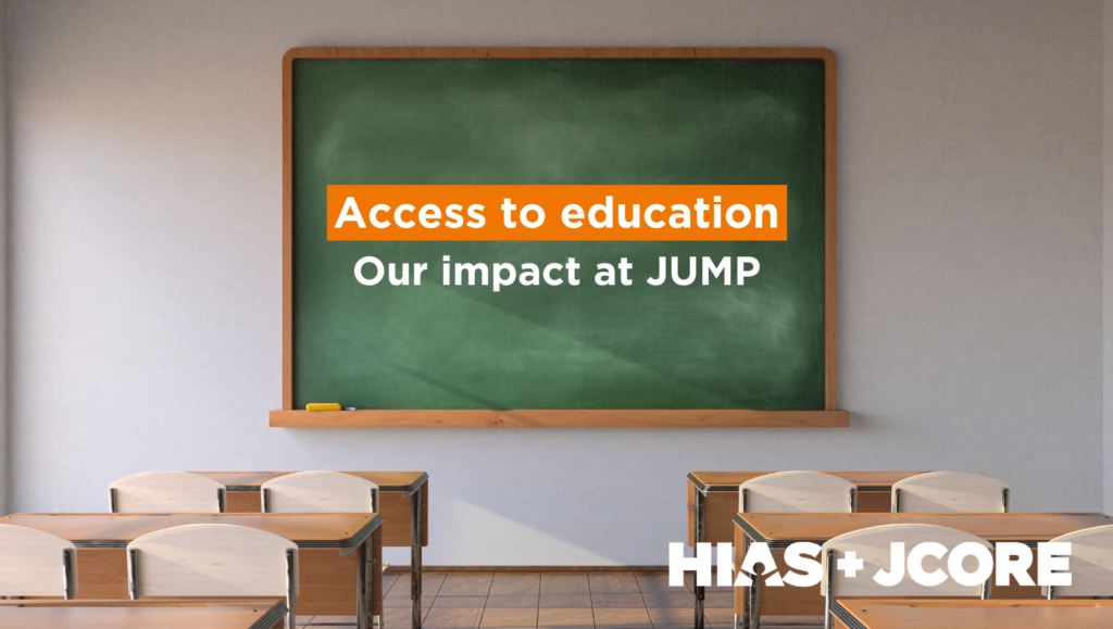 Empty classroom with rows of chairs and tables. A green chalkboard at the front of the room has text on it reading: "Access to education. Our impact at JUMP." The text is in white and the words "Access to education" are highlighted in orange.