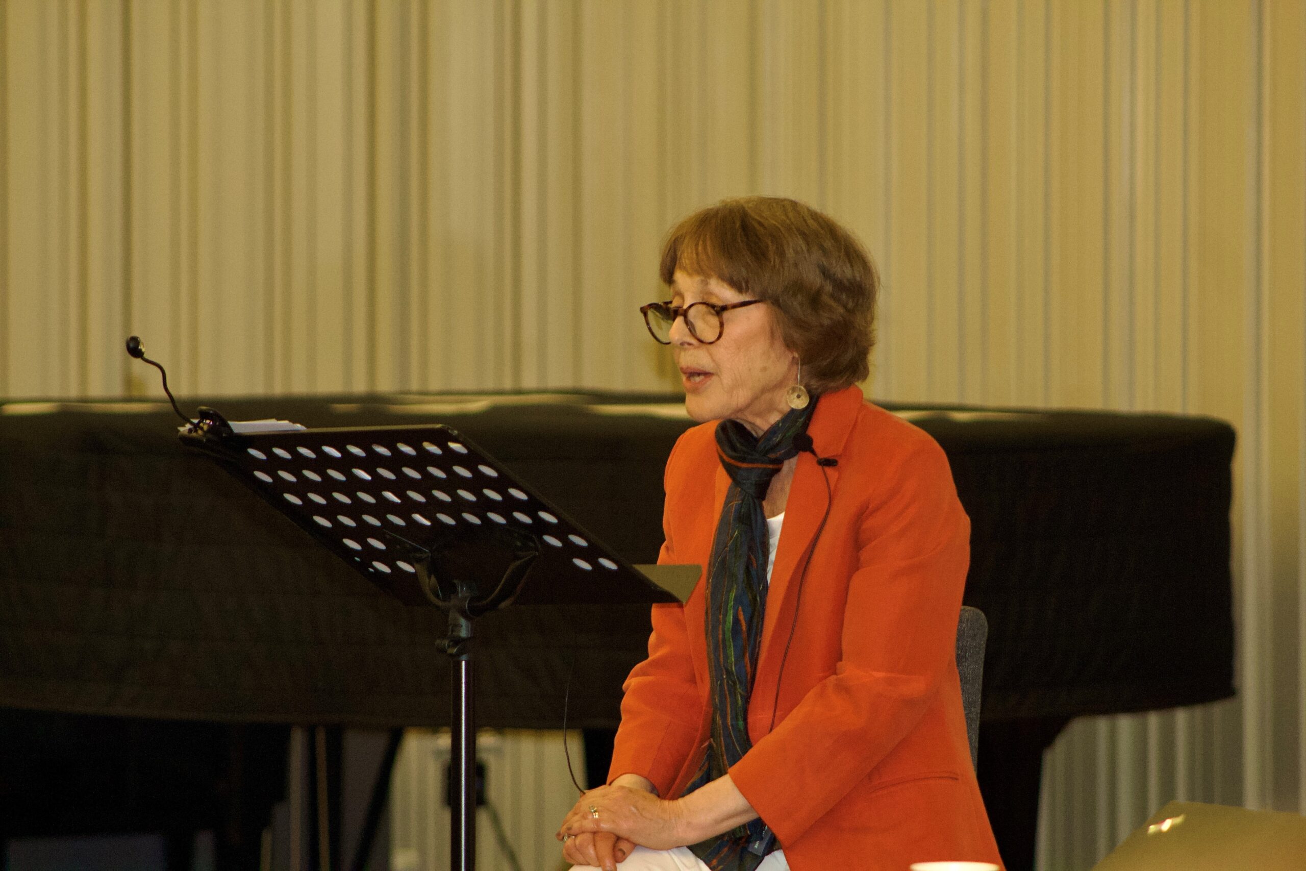 Edie Friedman (HIAS+JCORE's Honorary President) is sat on stage, speaking from a lectern.